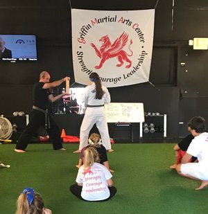 A martial arts student about to kick a board held firm by instructor 